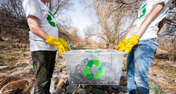 Two individuals standing together, each holding a recycling bin, promoting environmental awareness and recycling efforts